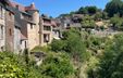 Photograph of the picturesque old town of Gargilesse, with historic houses set on hills surrounded by lush greenery and forest.