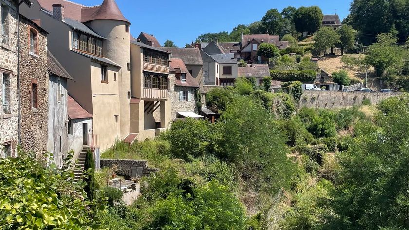 Photograph of the picturesque old town of Gargilesse, with historic houses set on hills surrounded by lush greenery and forest.