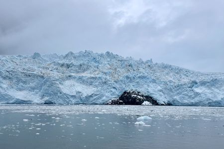 Arctic landscape, a mountain of ice taken from the water, where a small black surface of the earth is visible Arctic landscape, a mountain of ice taken from the water, where a small black surface of the earth is visible