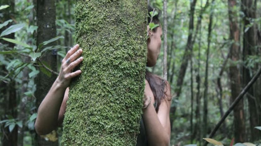 A woman is hugging a tree.