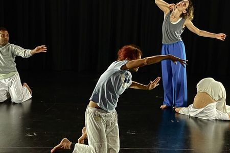 Photograph of four performers on a black stage, their bodies captured in different expressive poses. Photograph of four performers on a black stage, their bodies captured in different expressive poses.