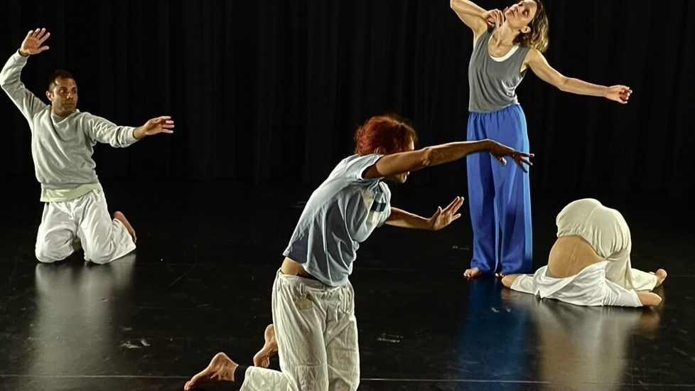 Photograph of four performers on a black stage, their bodies captured in different expressive poses. Photograph of four performers on a black stage, their bodies captured in different expressive poses.