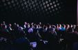 Audience seated in a hall listening to a presentation. Audience seated in a hall listening to a presentation.