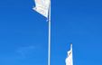 Photograph of white flags featuring thin graphic lines against a blue sky.