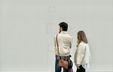 Photograph of two museum visitors looking at a wall covered with objects whose status as artworks or architectural elements is deliberately ambiguous.