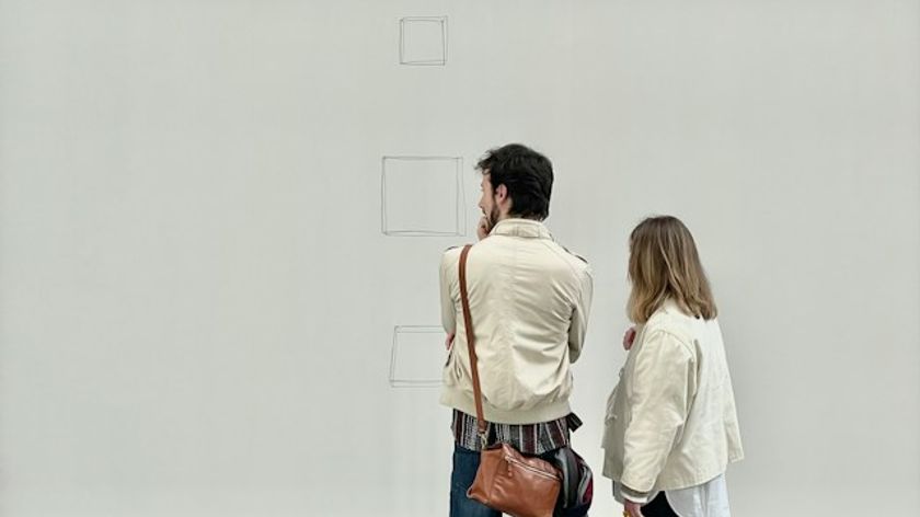 Photograph of two museum visitors looking at a wall covered with objects whose status as artworks or architectural elements is deliberately ambiguous.