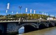 Esprit in Bayonne, a vaulted bridge lined with two rows of white flags featuring graphic designs as part of a public art installation.