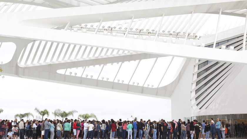 Photograph showing the scale of a museum entrance with white vaulted contemporary architecture and a large queue of people below.